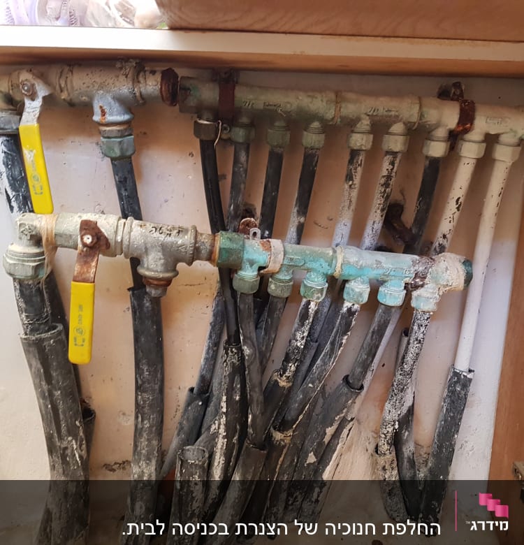 צינורות מים עם ברזים צהובים בארון מטבח